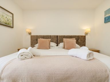 A bed with two pillows and rolled towels on a blanket in a bedroom at Birch in Truro