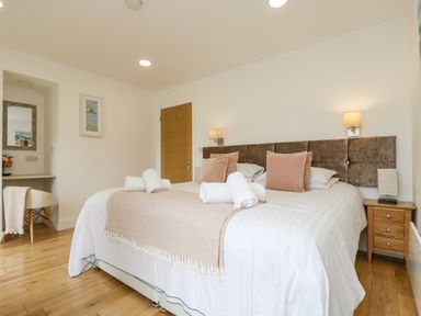 A bedroom with a double bed bedside tables a chair and a door at Birch in Truro