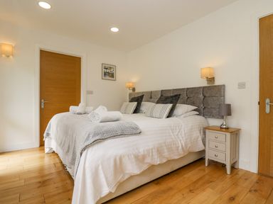 A bedroom with a double bed pillows bedside table and two wooden doors at Birch in Truro