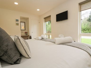 A bedroom with a bed with pillows and towels a wall-mounted TV and two windows at Birch in Truro