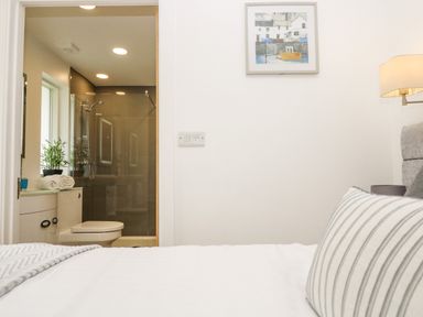 A bedroom with a view into a bathroom with a shower a toilet and towels at Birch in Truro
