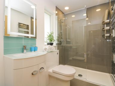 A bathroom with a toilet sink with mirror shower area and towel rack at Birch in Truro