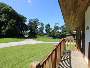 A wooden deck overlooking a grassy area with a gravel path and trees at Birch in Truro