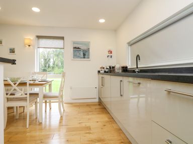 A kitchen with a dining table set with glasses and plates next to a window with blinds at Elm in Truro