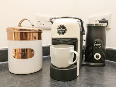 A kitchen counter with a biscuit jar a coffee machine with a cup and a milk frother at Elm in Truro