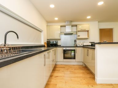 A kitchen with black countertops beige cabinets wooden floor and appliances at Elm in Truro