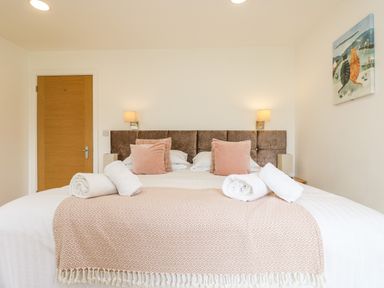 A bedroom with a double bed pillows rolled towels bedside lamps and a cat painting on the wall at Elm in Truro