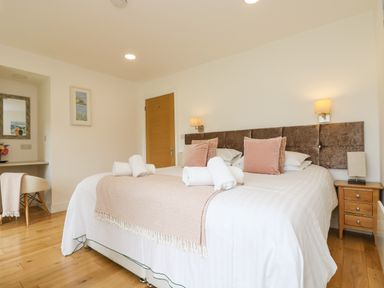 A bedroom with a double bed with rolled towels bedside tables and a desk with a chair at Elm in Truro