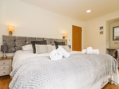 A bedroom with a large bed with pillows and folded towels bedside tables with lamps and a wooden door at Elm in Truro