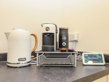 A kitchen countertop with a Breville kettle a Lavazza coffee machine coffee pods and a smart display at Hazel in Truro
