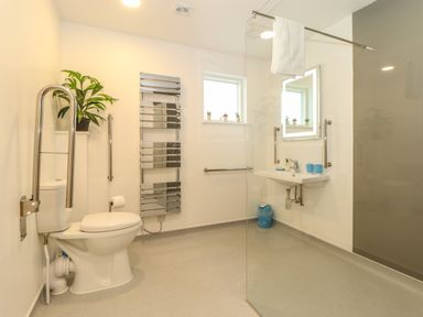A bathroom with a toilet a sink a heated towel rail a window and a glass shower partition at Hazel in Truro