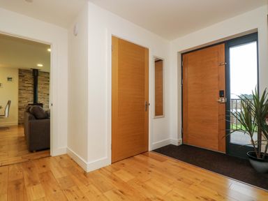 An entrance hallway with wooden doors a mirror a potted plant and visible adjoining living room at Juniper in Truro