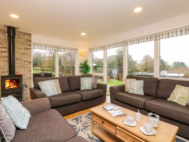 A living room with brown sofas, cushions, a wooden coffee table, and a fireplace at Juniper in Truro