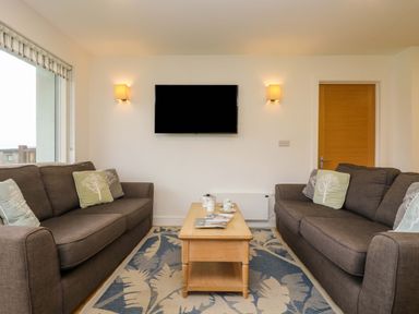 A living room with two brown sofas facing each other and a wooden coffee table between them at Juniper in Truro