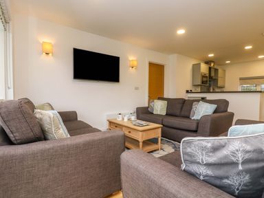 A living room with brown sofas a wooden coffee table and a wall mounted television at Juniper in Truro