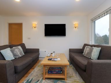 A living room with two sofas facing a wall mounted TV and a wooden coffee table in between at Oak in Truro
