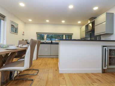 A kitchen and dining area with a wooden table and chairs and built in cabinets at Oak in Truro