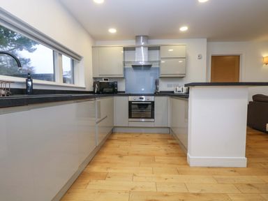 A kitchen with white cabinets black countertops wooden floor and appliances at Oak in Truro