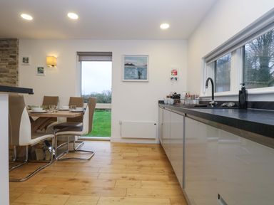 A kitchen with a dining table set with bowls and glasses next to a window at Oak in Truro