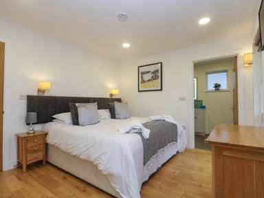 A bedroom with a large bed, bedside table with a lamp, and a wooden dresser at Oak in Truro