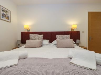 A bedroom with a double bed with pillows and towels on the bed two bedside tables with lamps and wall lights above the headboard at Oak in Truro