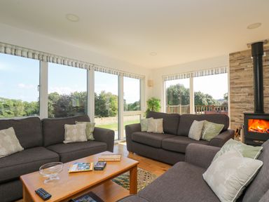 A living room with gray sofas a wooden coffee table and a wood burning stove at Rowan in Truro