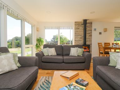 A living room with gray sofas and cushions around a wooden coffee table near a fireplace and dining area at Rowan in Truro