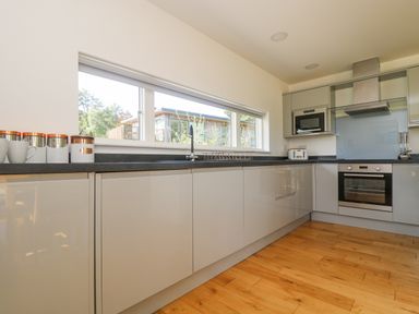 A kitchen with grey cabinets wooden floor and window with trees outside at Rowan in Truro