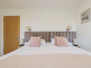 A bedroom with a bed with pink cushions and two lamps on side tables at Rowan in Truro