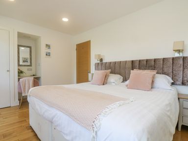 A bedroom with a double bed pink pillows and a chair at Rowan in Truro