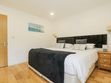 A bedroom with a double bed a black headboard and a wooden nightstand at Rowan in Truro