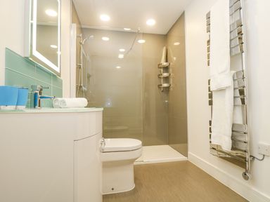 A bathroom with a toilet sink vanity and glass enclosed shower at Rowan in Truro