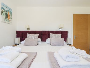A bedroom with a double bed two lamps a painting on the wall and wooden door at Willow in Truro