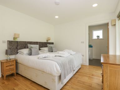 A bedroom with a double bed pillows bedside table and wooden dresser at Willow in Truro