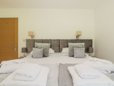 A bedroom with a double bed gray headboard bedside lamps and towels on the bed at Willow in Truro