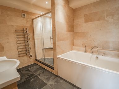 A bathroom with a bathtub a shower cabin a sink and a towel warmer at Boavista in Carnforth