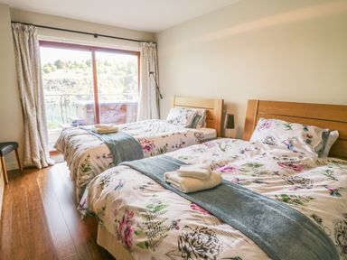 A bedroom with two beds with floral bedding and towels on them and a glass door overlooking water at Boavista in Carnforth