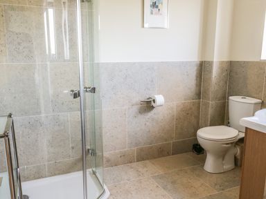 A bathroom with a glass shower enclosure a toilet a sink and tiled walls and floors at Boavista in Carnforth