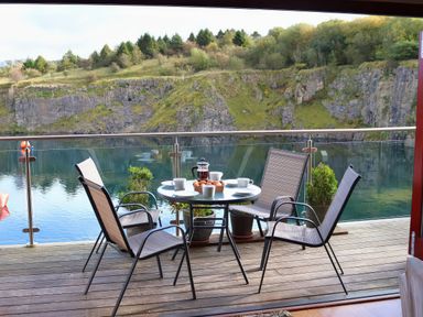 A balcony with a table and chairs overlooking a water body at Boavista in Carnforth