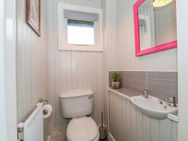A small bathroom with a toilet a sink a mirror and a small window at Sunset Lodge in Tattershall
