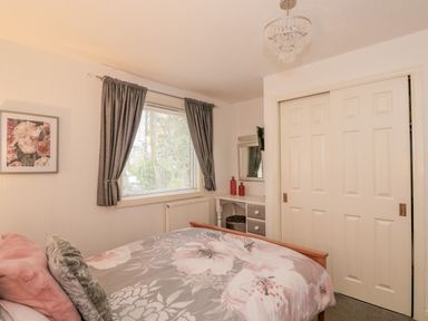 A bedroom with a bed a window with curtains a framed picture and a closet with sliding doors at Sunset Lodge in Tattershall