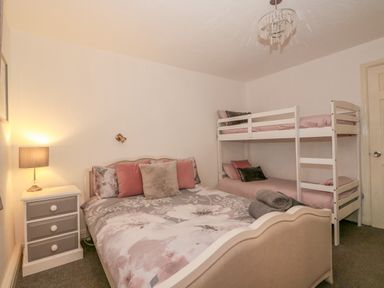 A bedroom with a double bed and a bunk bed with pillows and blankets next to a nightstand with a lamp at Sunset Lodge in Tattershall