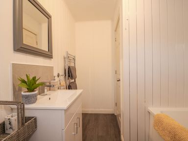 A bathroom with a sink cabinet a mirror a plant and towels at Sunset Lodge in Tattershall