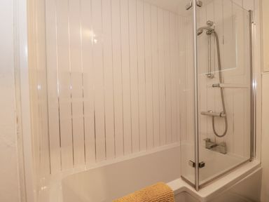 A bathroom with a bathtub shower and glass shower screen at Sunset Lodge in Tattershall