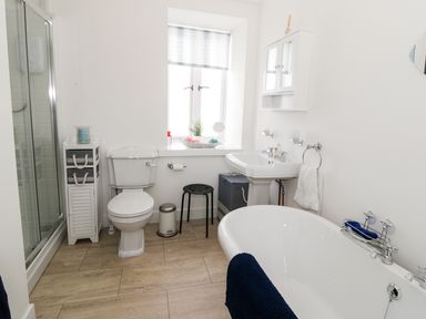 A bathroom with a bathtub a toilet a sink a shower and storage cabinets at Skovhaven in Catton