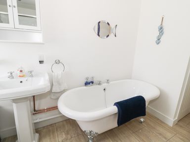 A bathroom with a freestanding bathtub a pedestal sink and a fish shaped mirror at Skovhaven in Catton