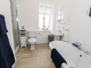 A bathroom with a bathtub a toilet a sink a shower and storage cabinet at Skovhaven in Catton
