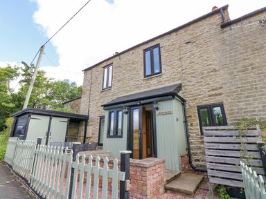 A stone exterior house with green painted porch and picket fence at Skovhaven in Catton