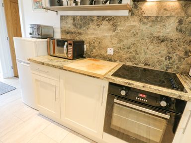 A kitchen counter with a toaster microwave cutting board stovetop and oven at Skovhaven in Catton