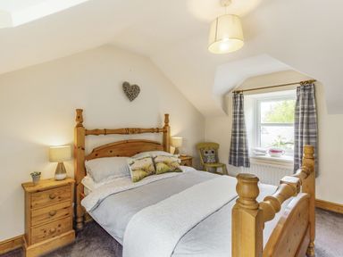 A bedroom with a wooden bed and bedside tables with lamps at Briar Cottage in Edlingham